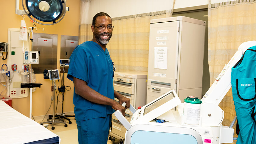 Clinician smiling at camera, standing with diagnostic equipment