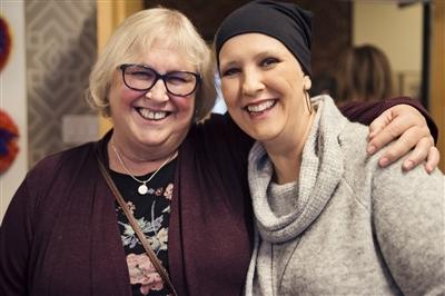 Two women, one with head cover, posed together and smiling for a photo