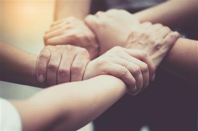 five hands all holding the next one&#39;s wrist in a sort of circle