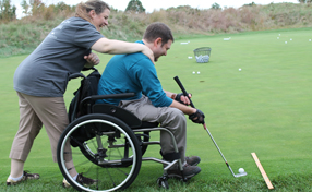 a wheelchair-bound man putting on the green