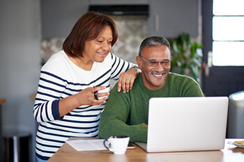 Older couple smiling at laptop computer