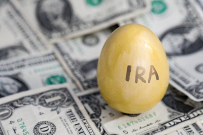 Gold painted egg with IRA written on it on top of dollar bills
