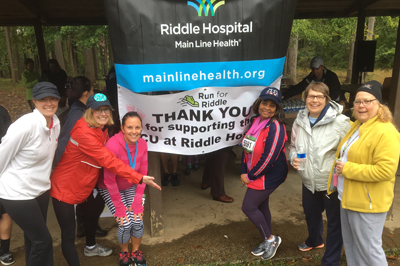 Group of ladies standing next to the Riddle Hospital logo and thank you for supporting the NICU at Riddle sign