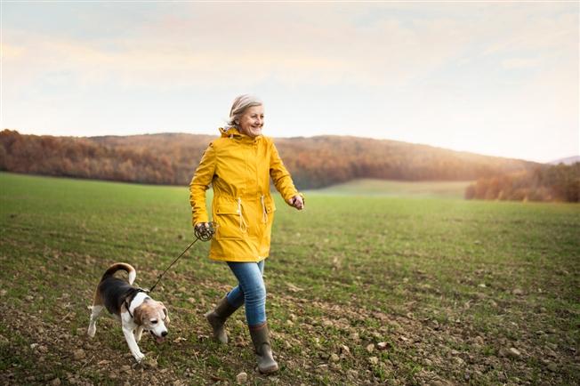 Senior woman with dog on a walk in an autumn nature