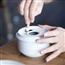 Person putting cigarette out on white ceramic ashtray