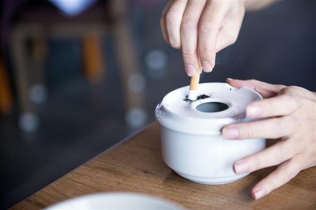 Person putting cigarette out on white ceramic ashtray Person putting cigarette out on white ceramic ashtray