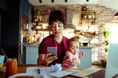 Woman holding baby and using phone