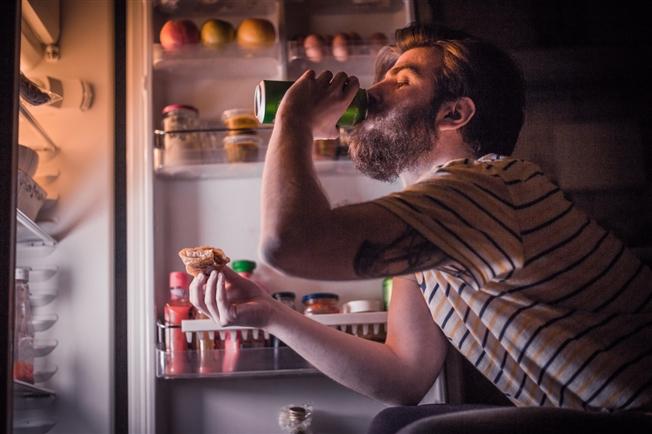 Person eating in front of open refrigerator door Person eating in front of open refrigerator door