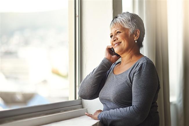 Older woman on the phone sitting next to a window