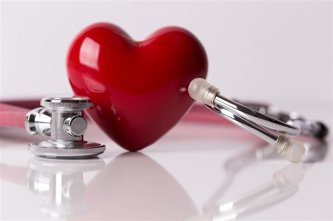 Plastic red heart sitting on table with stethoscope