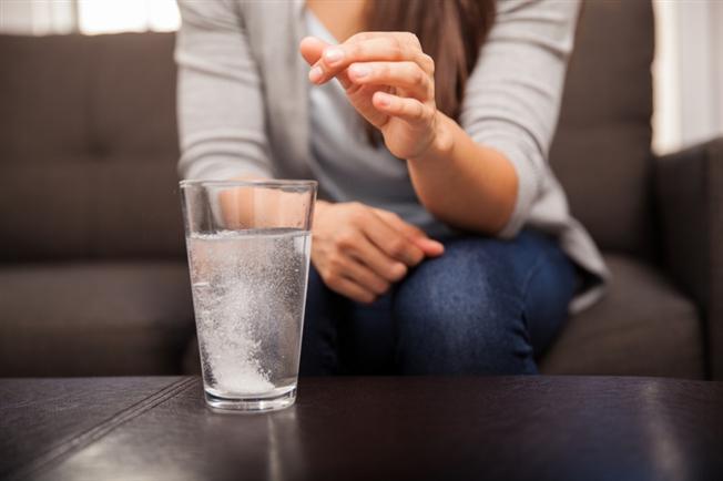 Woman dropping antacid into glass