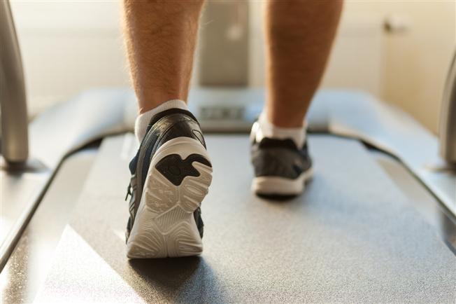 Shins down close up from behind of a person&#39;s feet walking on a treadmill