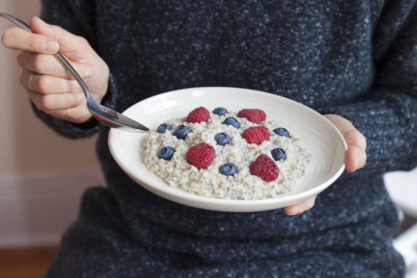 Woman eating oatmeal with raspberries