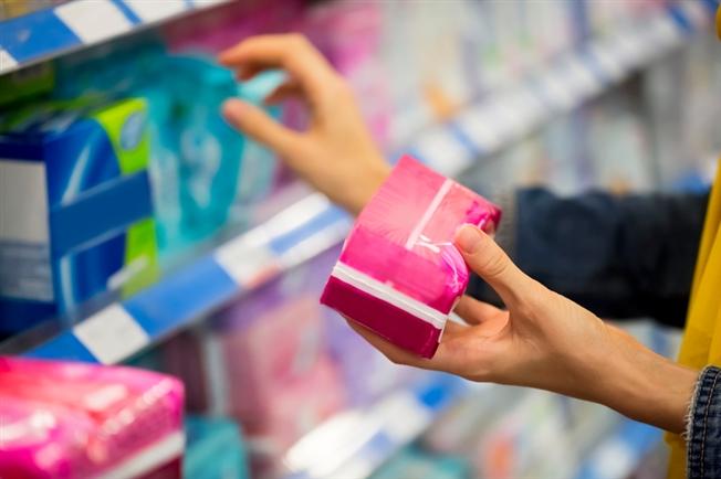 lady checking out pantyliner packages in the hygiene isle at the store