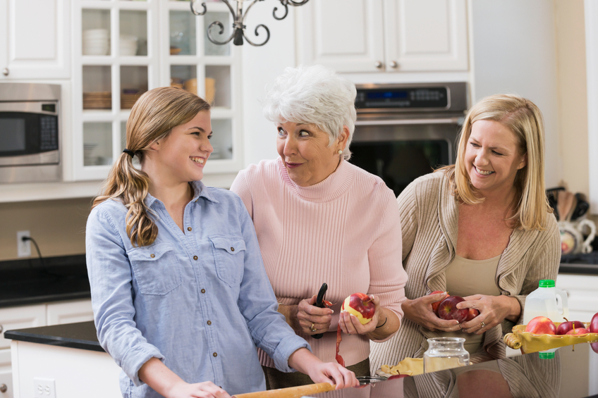 three generations of women preparing food in a kitchen