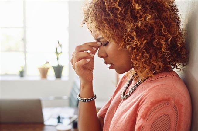 woman pinching bridge of nose between fingers with a pained look on her face