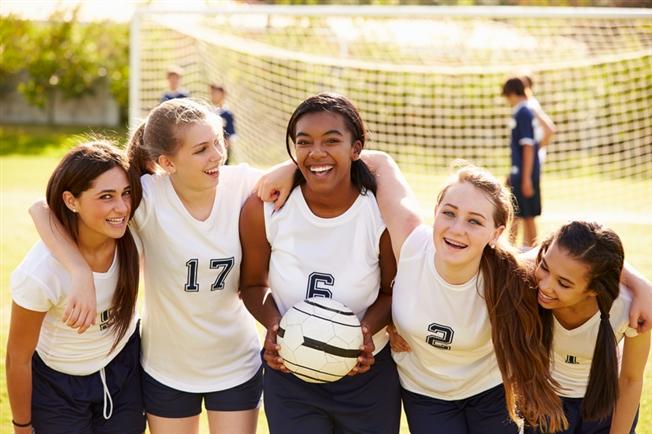 five young ladies posing for picture on soccer field