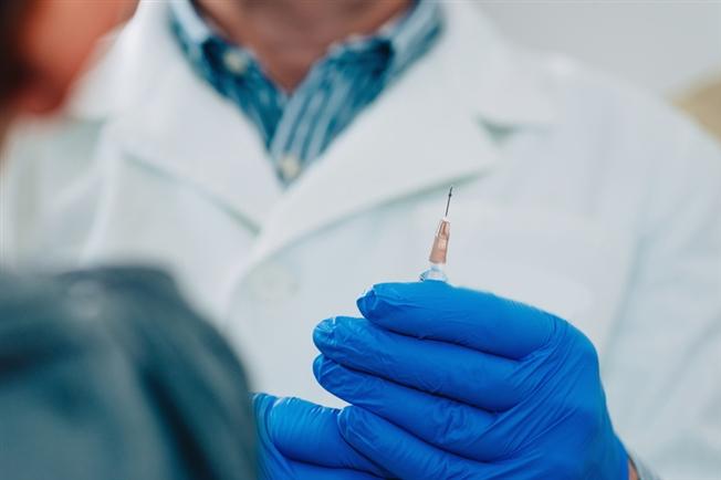 doctor in gloves holding up a needle