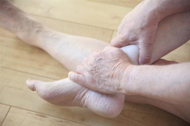 person cradling lower leg and ankle in their hands