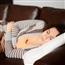 woman laying on couch, holding her stomach