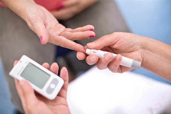 Nurse pricks a woman's finger, testing for diabetes.