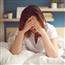 Girl in bed holding head in hands