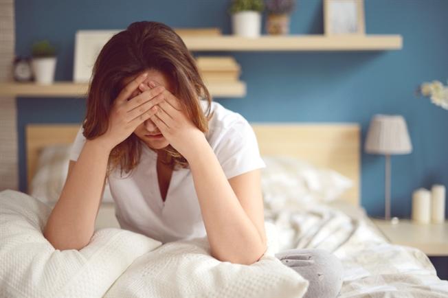 Girl in bed holding head in hands