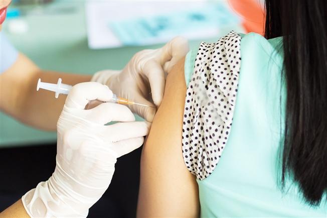 Woman getting vaccine in arm Woman getting vaccine in arm