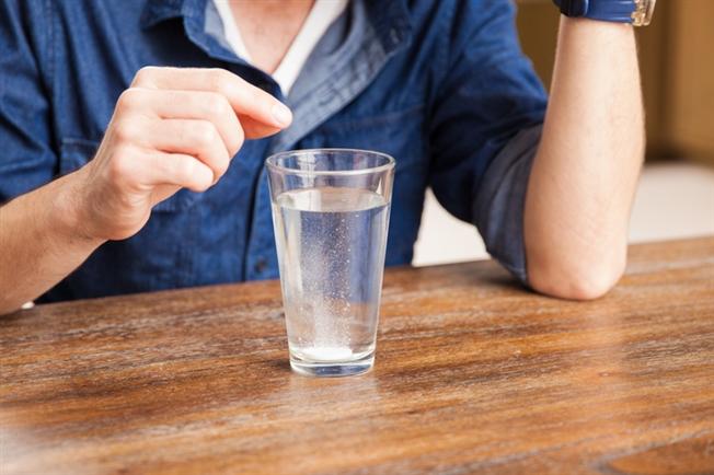 Close up on man right after dropping an antacid tablet in a glass of water Close up on man right after dropping an antacid tablet in a glass of water