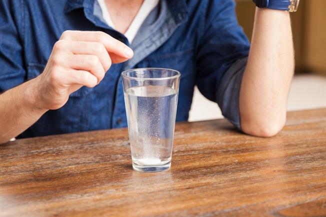 Close up on man right after dropping an antacid tablet in a glass of water