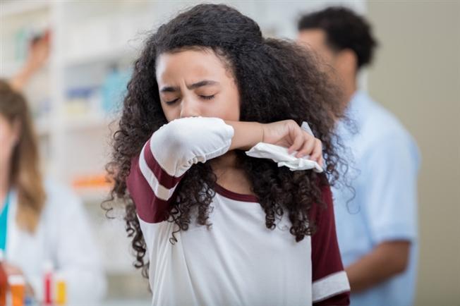 Young girl sneezing into arm Young girl sneezing into arm