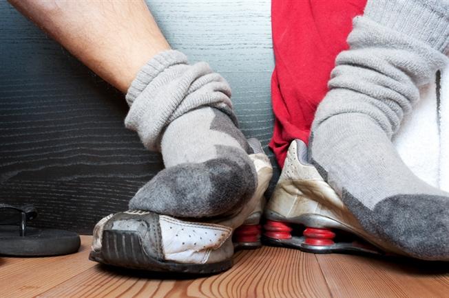 Sock covered feet resting on top of sneakers Sock covered feet resting on top of sneakers