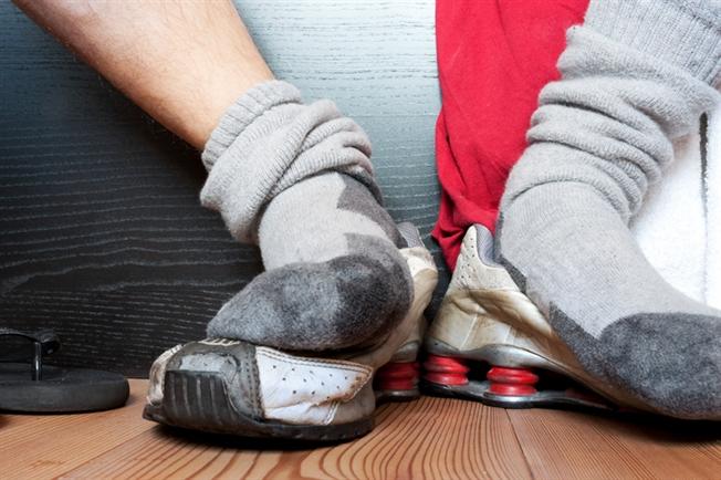 Sock covered feet resting on top of sneakers