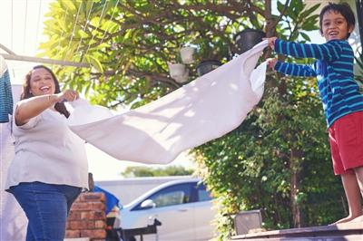 Woman and young boy folding up a white towel outside