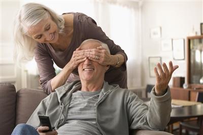 Senior woman covering spouse's eyes
