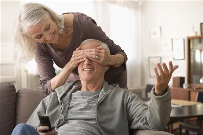 Senior woman covering spouse's eyes Senior woman covering spouse's eyes