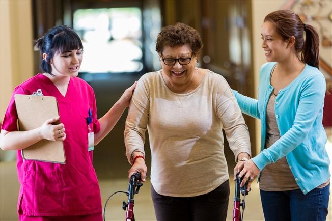 Therapists helping woman walk with a walker