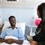 Man sitting in hospital bed talking with nurse standing next to him