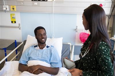 Man sitting in hospital bed talking with nurse standing next to him