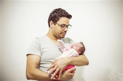 Father holding his baby and looking down at her Father holding his baby and looking down at her