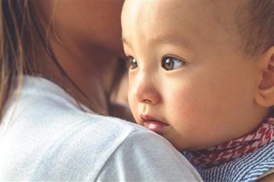 Close-up on a baby looking over his mother's shoulder