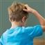 Little child shown from behind scratching at his head