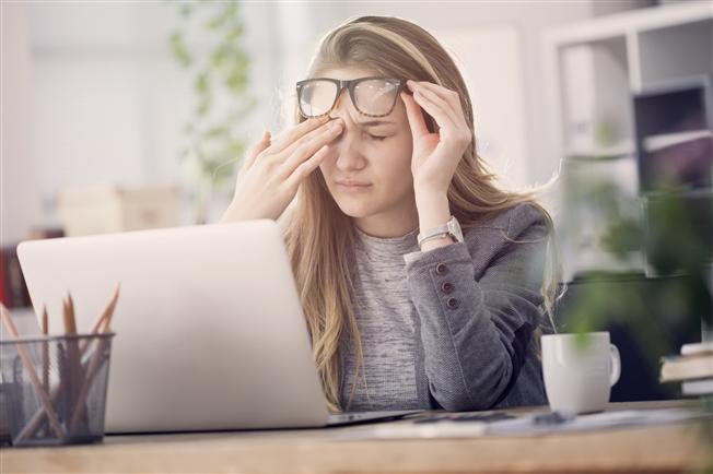 Woman rubbing eye at desk Woman rubbing eye at desk