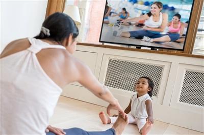Woman exercising in her living room with toddler