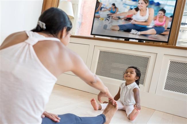 Woman exercising in her living room with toddler