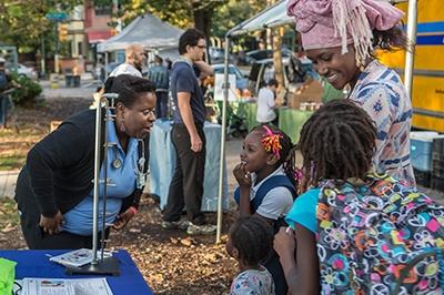 Health educator talking to family at community event Health educator talking to family at community event