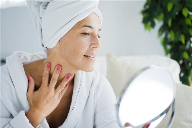 Woman examining skin in mirror