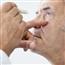 Close up of doctor looking at older gentleman&#39;s eye with pen light