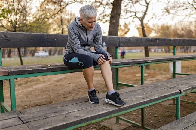 Person sitting down on bench inspecting leg Person sitting down on bench inspecting leg