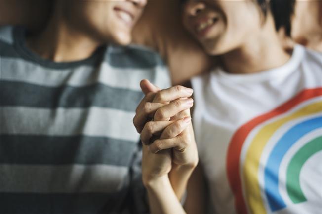 A couple holding their entwined hands up in front of camera